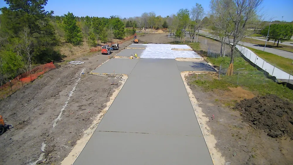 Aerial view of a long concrete driveway or access road framed by trees.
