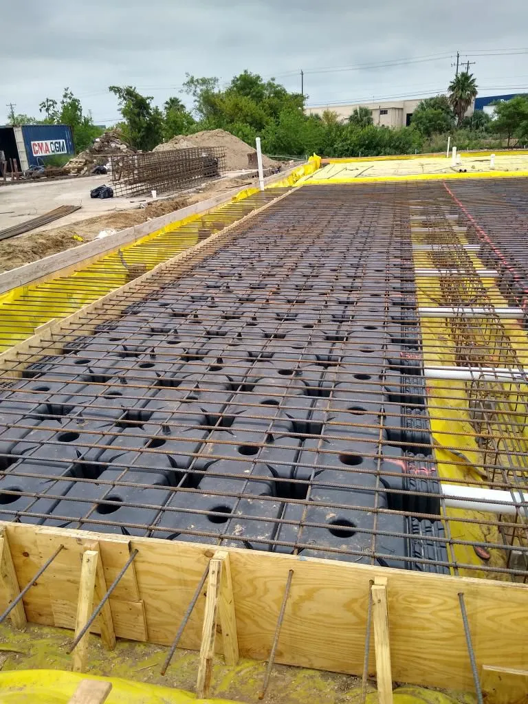 Rebar and formwork prepared for a concrete slab at an industrial site.